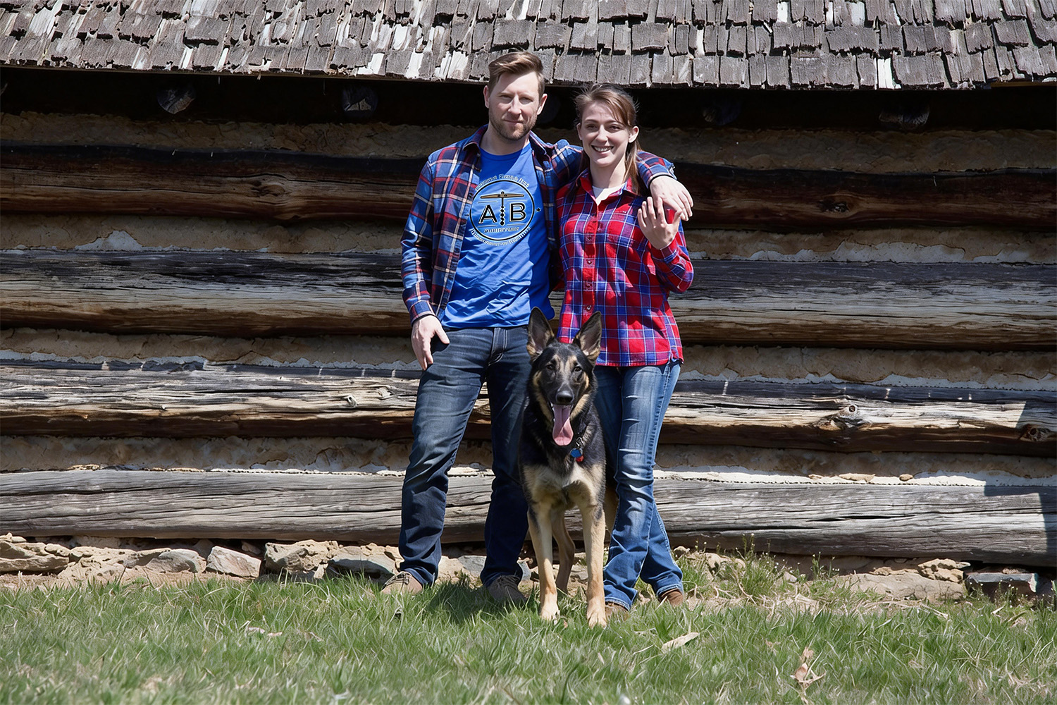 Jake, Raquel, and bear the dog in front of wooden structure 